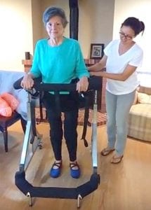 older woman safely supported in Gait Harness System at home